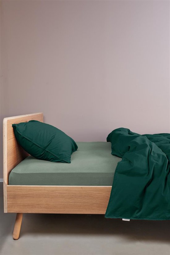 Lit avec un drap-housse vert et une couette vert foncé, un oreiller.