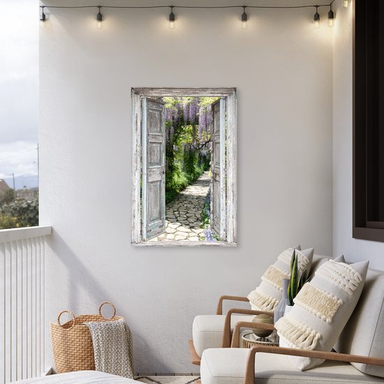 Een balkon met een tuinposter van een doorkijk door een open deur naar een bloeiend pad, met zitgelegenheid en sfeerverlichting.