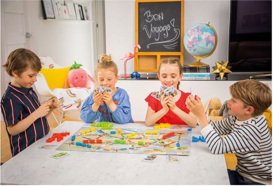 Gezin speelt Ticket to Ride: Mijn Eerste Reis. Kinderen en ouders aan tafel met speelbord en kaarten.