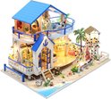 Miniatuur strandhuis met blauw dak, balkon en boot. Het huis heeft gedetailleerde kamers met meubels en accessoires.