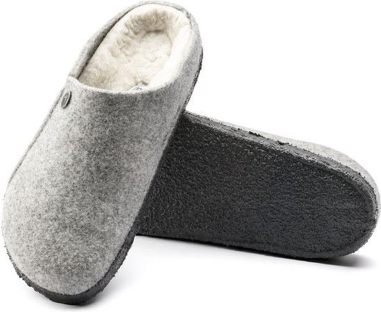 Grijze Birkenstock pantoffels van vilt met schapenwollen voering, de ene met zool omhoog.
