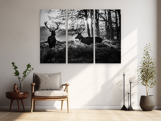 Peinture triptyque avec deux cerfs dans un environnement boisé, accrochée au-dessus d'un fauteuil.