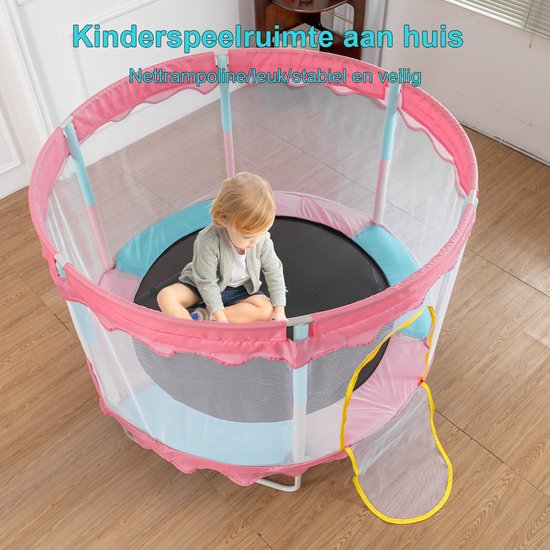 Klein meisje op een roze trampoline met veiligheidsnet en ballenbak, zittend met gekruiste benen.