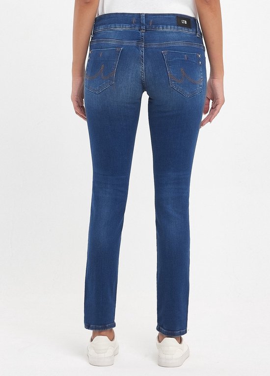 Achterkant van een vrouw in een rechte blauwe jeans met oranje stiksels en witte schoenen.