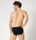 Achterkant model in zwarte Sloggi midi slip, logo tailleband.