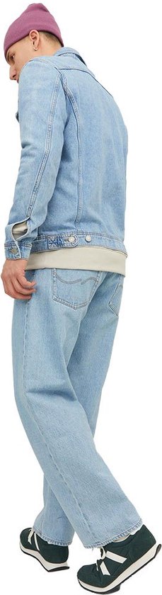 Man met roze muts, in lichtblauwe jeans en denim jack, met groene sneakers.