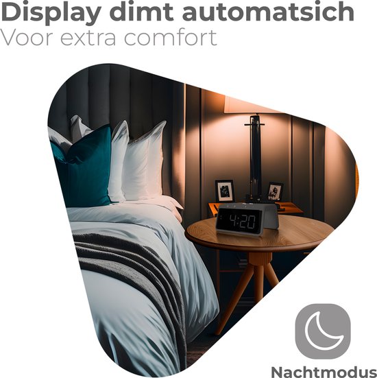 Digitale wekker met zwart display op nachtkastje naast een bed.