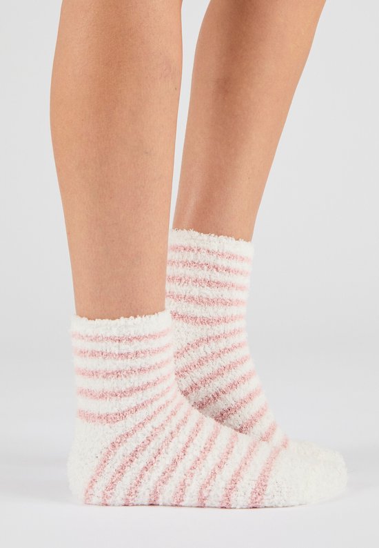 Voeten van een vrouw in zachte, pluizige sokken met roze en witte strepen.