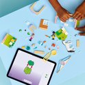 Des mains d'enfants construisent une clinique vétérinaire LEGO Friends, avec figurines, animaux et une tablette d'instructions.