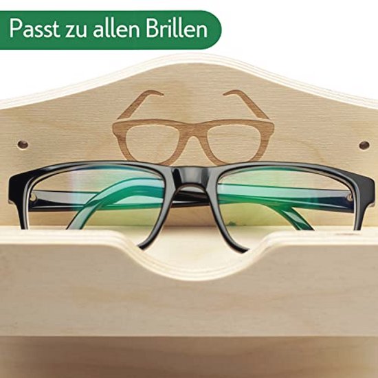 Zwarte bril met groene glazen rustend in een houten brillenhouder met een gegraveerd bril-icoon.