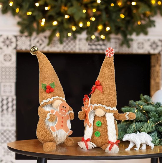 Twee kerstkabouters met gingerbread-thema op een tafel, met kerstboom en haard op de achtergrond.