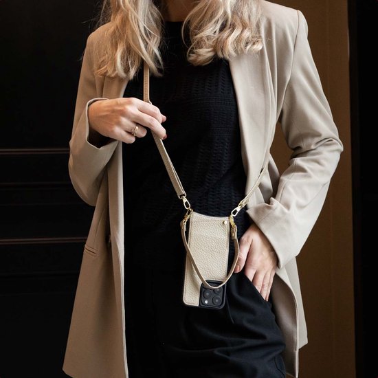 Beige telefoonhoes met schouderkoord gedragen door een vrouw met beige blazer.