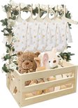 Houten babymand met rompertjes, teddybeer, konijn en bloemendecoratie.