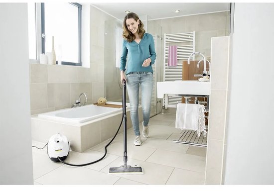 Femme utilisant un nettoyeur vapeur dans une salle de bain carrelée de blanc.