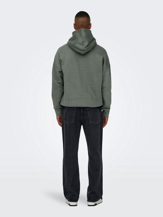 Man van achteren gezien, met een groene hoodie en wijde, zwarte spijkerbroek met stonewashed look.
