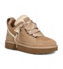 Zij-voorkant van beige UGG sneakers met ruitvormige veters, wollen voering en hoge zool.