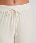 Close-up van een witte pyjamabroek met een geknoopt trekkoord bij de taille.