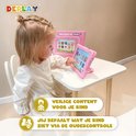 Meisje met knotjes zit aan tafel, speelt op roze tablet