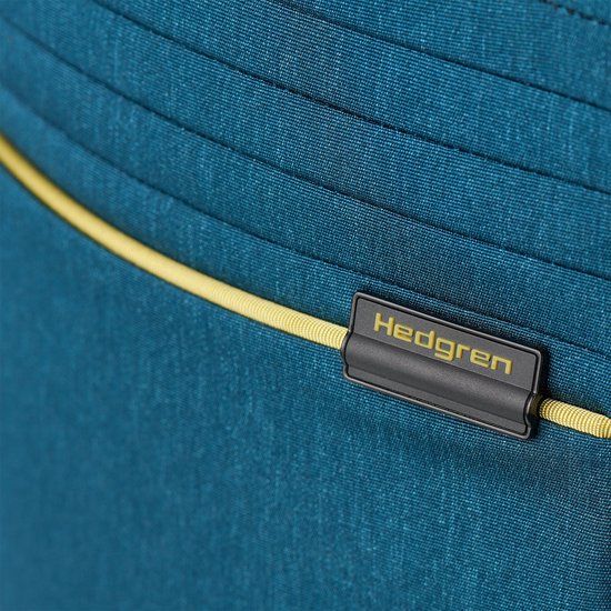 Close-up van blauw Hedgren rugzakmateriaal met gele bies en logo.