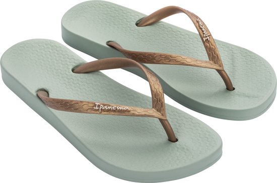 Een paar lichtgroene Ipanema slippers met koperkleurige bandjes en het "Ipanema" logo.