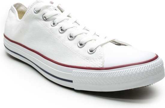 Enkele witte lage Converse sneaker met witte veters en rode en blauwe strepen op de zool.