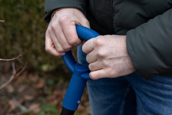 Man met blauwe jas houdt het blauwe D-handvat van een spade vast.