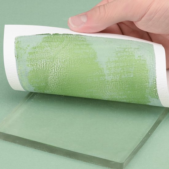 Een hand trekt papier met een groene afdruk van tekst omhoog van een transparante gelplaat.