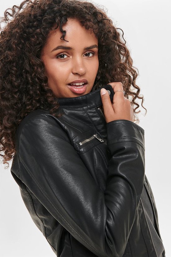 Close-up van een vrouw met krullend haar in een zwart faux leren bikerjack met ritsen.