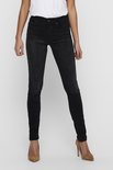Model in een strakke zwarte jeans met hoge taille, witte top en bruine pumps.