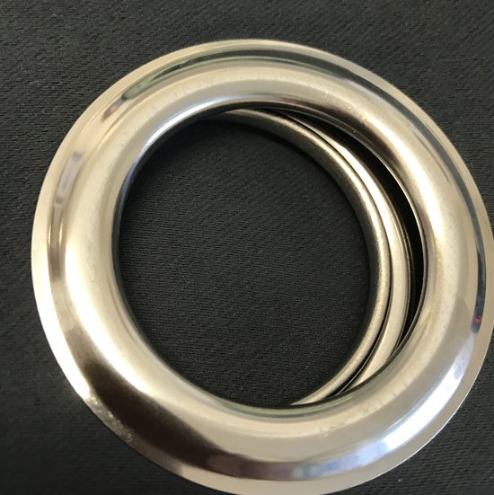 Drie zilverkleurige, metalen gordijnringen met een glanzende afwerking op een zwarte achtergrond.