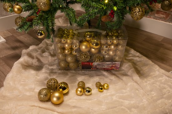 Kerstboom versierd met gouden kerstballen. Een doos met kerstballen ligt onder de boom.