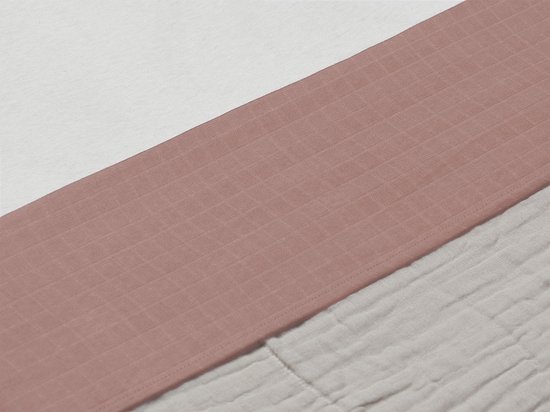 Detail van het wieglaken met roze band en beige gekreukelde stof.
