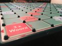 Close-up van een Scrabble XL bord met rode '2x Woord' en '3x Woord' vakjes.