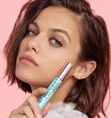 Jonge vrouw met bruin haar en groene ogen houdt een lichtblauwe Lash Paradise Waterproof mascara vast.