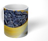 Mok - Zonnebloempitten in een gele kom met een paar gevallen zonnebloempitten - 350 ML - Beker