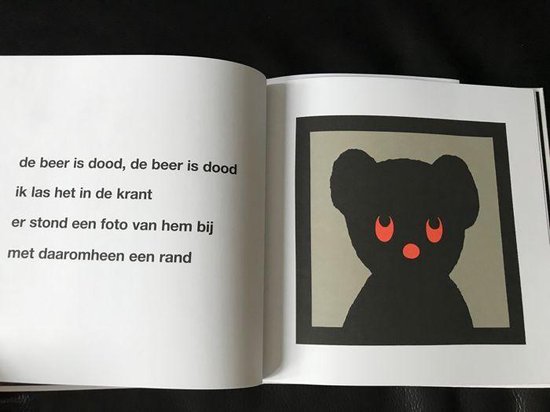 Een opengeslagen boek met een portret van een zwarte beer met rode ogen.