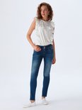 Model met krullend rood haar in blauwe jeans met knoopsluiting.