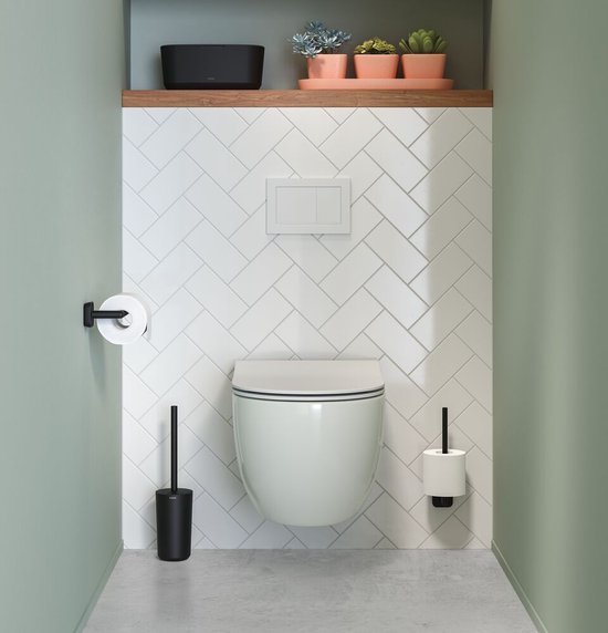 Badkamerinterieur met een zwevend toilet, witte tegels en diverse zwarte accessoires.