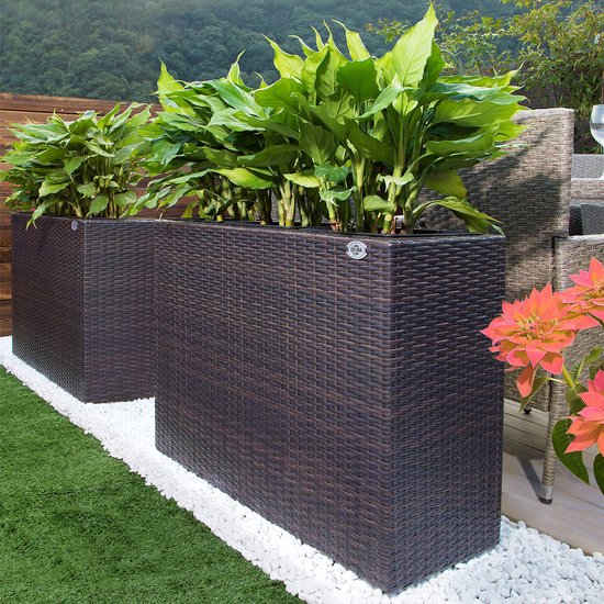 Twee bruine plantenbakken met wicker-look, gevuld met planten, in een tuin.