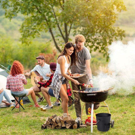 Koppel bij barbecue, man geeft vrouw spiesjes met vlees en groenten.