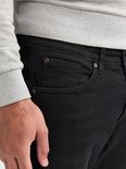 Detail van een zwarte jeans met zak, knoopsluiting en label.