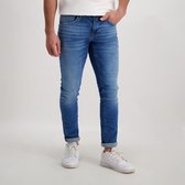 Een man draagt een spijkerbroek met lichte wassing, omgeslagen pijpen en sneakers.