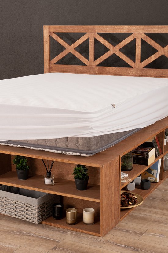 Een waterdichte matrasbeschermer met rondom elastiek op een houten bed met opbergvakken.