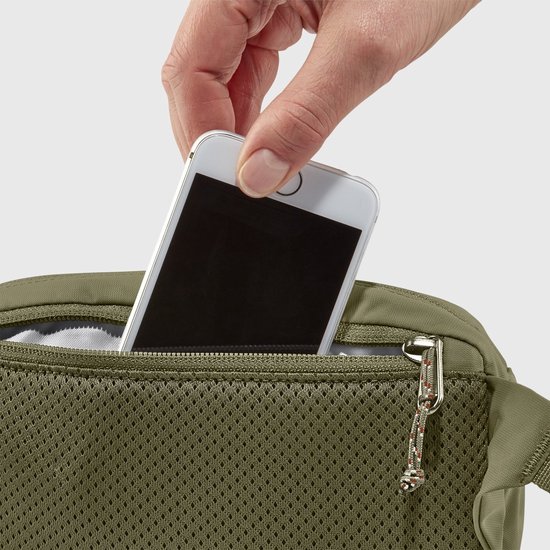 Hand plaatst smartphone in een gaasvak van een olijfgroene heuptas.