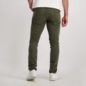 Man met groene corduroy jeans en witte sneakers, van achteren gezien.
