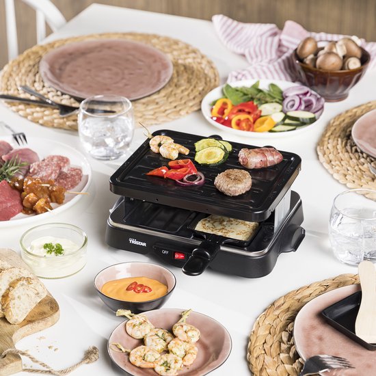 Gourmetset op een tafel met hapjes: biefstuk, garnalen, groenten en kaas.