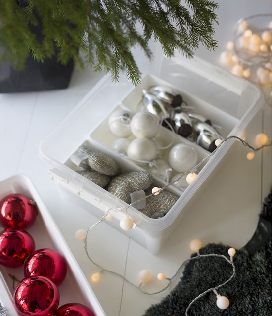 Transparante opbergbox met vakverdelers, gevuld met kerstballen en slingers.