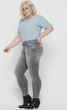 Vrouw in grijze skinny jeans met rafelende zoom en lichtblauwe t-shirt.