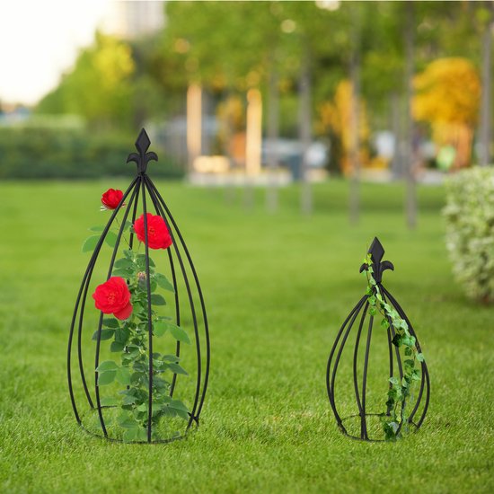 Twee zwarte metalen plantenrekken in een groene tuin, één met rozen.