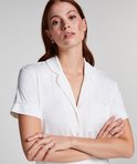 Model met rode haardos en sproeten, gekruiste armen, in een wit pyjamashirt met korte mouwen, kraag en borstzakje.